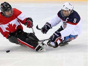 Team Canada's Ben Delaney (left) and Andy Yohe of the United States battle for the puck during their sledge hockey semifinal at the 2014 Winter Paralympics in Sochi, Russia, on Thursday, March 13, 2014.