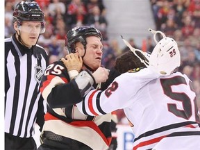 Chris Neil of the Ottawa Senators fights against Brandon Bollig of the Chicago Blackhawks during first period of NHL action at Canadian Tire Centre in Ottawa, March 28, 2014.