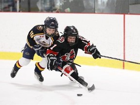 Jake Campbell #10 of the Burlington Eagles barrels for the puck against Andrew Lafrance #11 of the Nepean Raiders during opening day Minor Atom AA boys hockey action at Bell Sensplex, in Ottawa, ON, on December 28, 2013.  Photo by Jana Chytilova