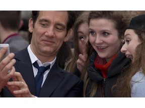 British actor Clive Owen takes a photo with fans as he arrives for for We Day at Wembley Arena in London, Friday, March 7, 2014. Organized by international charity and educational partner, Free The Children, We Day is a global event with more than 160,000 youths coming together in stadium gatherings around the world to take part in an unprecedented educational initiative which inspires students to get involved in positive social change.
