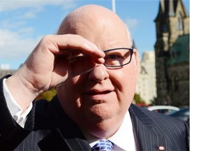 Sen. Mike Duffy shields his eyes as he arrives at the Senate on Parliament Hill in Ottawa on Tuesday, Oct. 22, 2013.