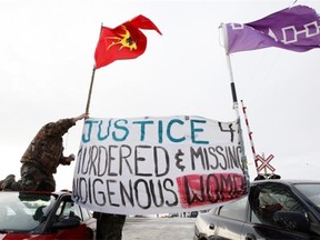 Native protesters rise a banner during a demonstration at the rail line at Wyman’s Road near Shannonville, Ont., east of Belleville, on Wednesday.