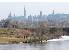 People walk along the Ottawa River with their dogs Sunday morning.