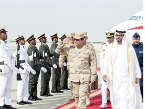 A picture made available by the United Arab Emirates’ official news agency WAM shows Egyptian Defense Minister and Military Chief General Abdel Fattah al-Sisi (C) saluting as he is welcomed by Sheikh Mohamed bin Zayed Al Nahyan Crown Prince of Abu Dhabi (R) upon his arrival in Abu Dhabi on March 11, 2014.  AFP PHOTO/WAM/HO