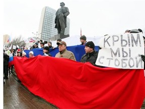 Pro-Russian activists hold a Russian flag and a placard reading “Crimea we are with you” during their rally in eastern Ukrainian city of Donetsk on March 16, 2014. Polls opened in Crimea on March 16 for a unique referendum to break away from Ukraine and join Russia, with the first voters seen entering polling stations in the regional capital Simferopol. Ukraine’s new government and most of the international community except Russia have said they will not recognise a result expected to be overwhelmingly in favour of immediate secession.