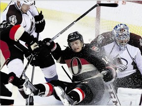 Senators forward Colin Greening, centre, is checked into Colorado Avalanche goaltender Semyon Varlamov during the second period Sunday.