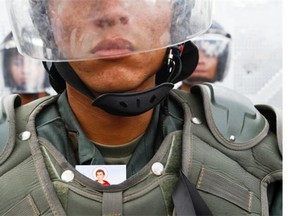 In this Sunday, March 16, 2014 photo, a prayer card peeks out from the body armor of a Bolivarian National Guardsman during an anti-government march, in Caracas, Venezuela. Anti-government street protests by Venezuelans fed up with violent crime, shortages of basic items such as flour and cooking oil and high inflation have roiled Venezuela for more than a month. (AP Photo/Esteban Felix)