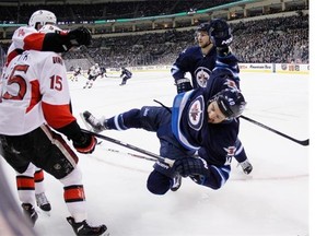 Winnipeg Jets’ Devin Setoguchi (40) gets levelled by Ottawa Senators’ Chris Phillips (4) as Sens Zack Smith (15) and Jets Michael Frolik (67)look on during second period NHL action in Winnipeg on Saturday, March 8, 2014.