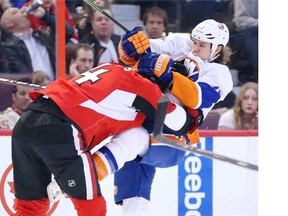 Chris Phillips of the Ottawa Senators hits Matt Martin of the New York Islanders during second period of NHL action at Canadian Tire Centre in Ottawa on Apr. 2, 2014.