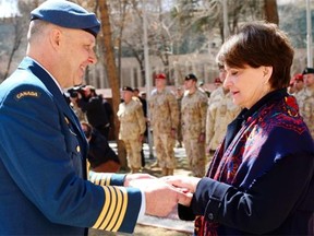 Colonel Robert Spencer, the Canadian Defence Attach of Afghanistan, hands over the folded Canadian flag to Deborah Lyons, Canada’s Ambassador to the Islamic Republic of Afghanistan, as a symbol of the continued Canadian support to Afghanistan during the flag lowering ceremony on March 12, 2014 at International Security Assistance Force (ISAF) headquarters.