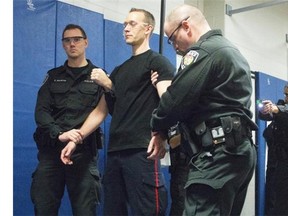 Const. Keith Martin, left, and Const. Dave Cameron support Const. Ryan Weselake moments before he was Tasered by Const. P. Tella during a demonstration for media at Algonquin College last December.