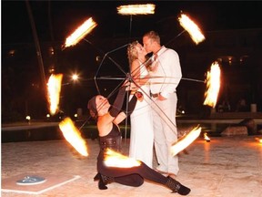 A fire dancer frames Oksana and Ryan kissing at the reception.