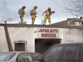 Firemen examine the roof of an auto repair shop on Breezehill Avenue following a Wednesday morning fire.