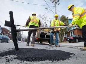 From left, Jacques Landriault, Julien Legros and Denis Frederick work along McKay Street in New Edinburgh as work crews continue filling potholes around the city.