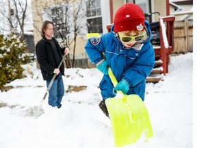 Jack D’Orgeville helps his father Marc shovel the snow in front of their house on March 30, 2014 as up to 15 cm of late season snow blankets Ottawa.