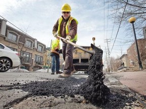 Jacques Landriault dumps asphalt into a pothole on McKay Street in New Edinburgh as work crews continue filling potholes around the city.