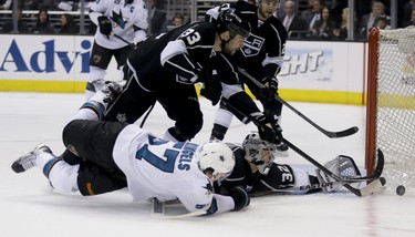 Los Angeles Kings goalie Jonathan Quick (32) blocks shot by San Jose Sharks center Tommy Wingels as Willie Mitchell looks on during the first period in Game 4 of an NHL hockey first-round playoff series in Los Angeles, Thursday, April 24, 2014. (AP Photo/Chris Carlson)