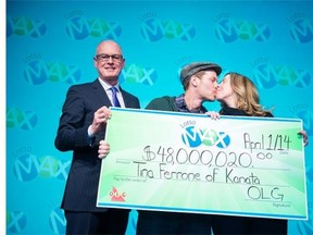 Liam McGee and Tina Ferrone, both 42, of Kanata collected their $48-million Lotto Max prize on Tuesday in Toronto. OLG senior vice-president of lottery Greg McKenzie, left, presented the symbolic cheque.
