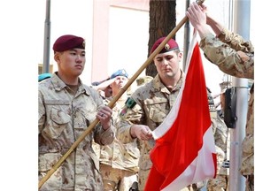 Master Cpl. Daniel Choong, left, Cpl. Harry Smiley and Cpl. Gavin Early, at right, take down the Canadian flag for the last time in Afghanistan on March 12, bringing an end to 12 years of military involvement in a campaign that cost the lives of 158 Canadian soldiers.