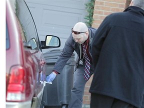 Ottawa police investigators photograph a minivan outside the home of prominent realtor Chris Hoare in Orleans on Thursday.