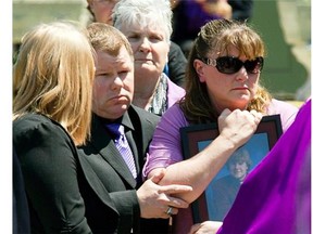 Patrick Leighton, centre, and his wife Sheri, clutching a photo of her son, Eric, while their daughter Kaitlyn looks on at Eric Leighton’s funeral. Nearly two years to the day of an explosion in a Barrhaven high school that killed Eric Leighton, the family is suing his teacher and the Ottawa Catholic School Board.