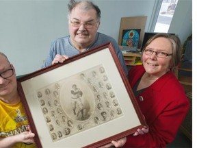 Randy Lamont, left, Joe Donegan and L’Arche Ottawa executive director Donna Rietschlin hold a rare framed photo of the 1900 Ottawa Rough Riders that writer Dan Turner is auctioning as a fundraiser for L’Arche.