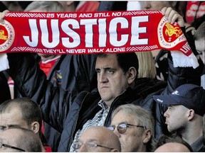 A man holds a scarf calling for justice, during a minute of silence at Tuesday's memorial service on the 25th anniversary of the Hillsborough soccer disaster, at Anfield Stadium, in Liverpool, England.