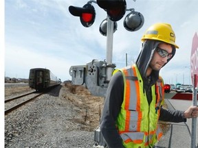 Ward Coun. Jan Harder watches as a railway worker with a stop sign manually keeps pedestrians off the tracks at the Fallowfield crossing in Barrhaven as a train passes.
 Harder visited five railway crossings in Barrhaven on Friday.
