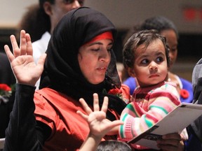 Mehreen Irum Shahid swears allegiance to Canada holding her daughter Zohra at a citizenship ceremony in 2010. -(Bruno Schlumberger / Postmedia News)