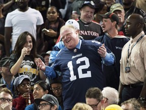 Toronto Mayor Rob Ford laughs with fans as he attends the Toronto Argonauts and Hamilton Tiger-Cats CFL Eastern Conference final football game in Toronto on Sunday, Nov. 17, 2013. A quartet of self-described "knuckleheads" celebrated a journalistic touchdown Thursday as they nabbed a timely, unexpected interview with Ford.THE CANADIAN PRESS/Nathan Denette