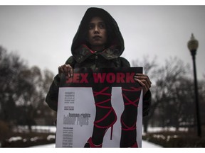 A woman holds a sign saying "Sex Work is Real Work" during a rally at Allan Gardens park to support Toronto sex workers and their rights in Toronto, Friday Dec. 20, 2013.