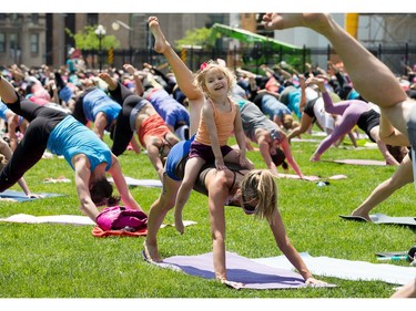 Alicia O'Dell, 3, enjoys a ride on her mom Laura O'Dell's back as Lululemon continues with their annual Wednesday ritual of noontime yoga exercise on Parliament Hill. Photo taken at 12:33 on May 21, 2014.