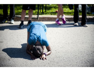 An elite woman in the marathon crumbles to her knees after finishing her run at Ottawa Race Weekend Sunday May 25, 2014.