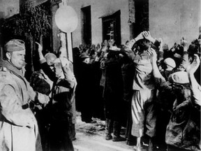 September 1942:  This photograph, of a raid on the Jewish ghetto in Warsaw, was found on the body of a German soldier killed on the Russian front. During such raids Jews were lined up in the streets and forced to stand facing a wall with their hands above their heads for long periods. Gestapo agents on the left are searching some of the victims.