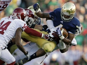 In this Sept. 28, 2013, photo, Notre Dame's George Atkinson III (4) is tackled by Oklahoma's Geneo Grissom, behind, during an NCAA college football game in South Bend, Ind.