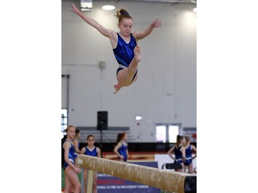 Grace MacDonald (Alberta) flies high above the beam as she practices her routine.
