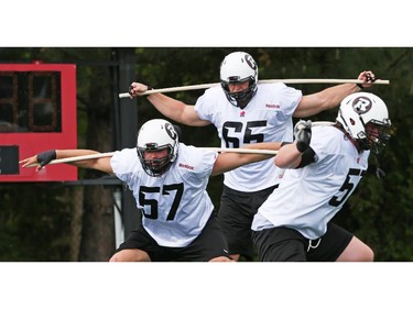 Hugo Desmarais (L), #65 Nate Menkin and Aaron Wheaton (R) go through a drill during the opening day for the RedBlacks rookies training camp, May 28, 2014.