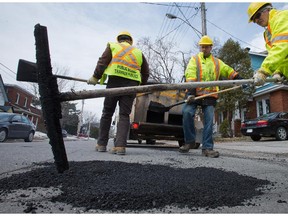 From left, Jacques Landriault, Julien Legros and Denis Frederick work along McKay Street in New Edinburgh as work crews continued filling potholes around the city in April.