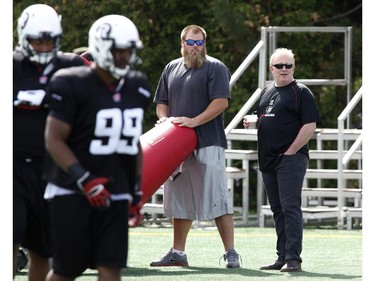 Jeff Hunt (R), president of OSEG (the owners of the Redblacks franchise) watches the CFL Ottawa Redblacks rookie camp with offensive lineman Jon Gott (C) at Keith Harris Stadium in Ottawa on Friday May 30, 2014.