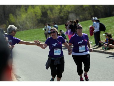 Jennifer Simpson reaches for a high five as she links hands with Andrea Young during the Shoppers Drug Mart Run for Women on Sunday, May 11, 2014 near the Aviation Museum. The 5K. 10K, and 1k for children helps raise money for Women's Mental Health programs in race cities, such as Royal Ottawa.