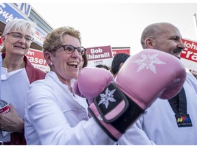 Ontario Liberal leader Kathleen Wynne shows off a pair of boxing gloves she received as a gift, while her partner Jane Rounthwaite (left) looks on, during a campaign stop in Ottawa South, the riding of John Fraser (right) and former riding of Premier Dalton McGuinty, in Ottawa on Wednesday, May 7, 2014.