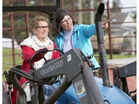 Ontario Premier Kathleen Wynne drives a tractor with instruction from farmer Sandra Vos (right) at a campaign event in Paris, Ontario on Tuesday May 20, 2014.