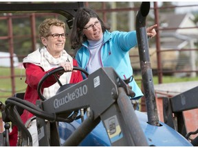 Ontario Premier Kathleen Wynne drives a tractor with instruction from farmer Sandra Vos at a campaign event in Paris, Ontario on Tuesday May 20.