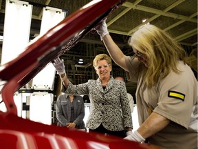 Ontario Premier Kathleen Wynne looks under the hood of a Toyota car as she talks with an employee at the Toyota  assembly plant during a campaign stop in Cambridge on Wednesday, May 21, 2014.