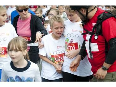 Marco Goguen gets some help from Angela Goguen and medics after he fell during the kids marathon at Ottawa Race Weekend Sunday May 25, 2014.