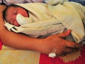 A newborn baby is prepped and handed to the mother moments after delivery inside a birthing room at Nazareth House on May 10, 2013 in Manila, Philippines. The Nazareth home take in women who are expecting mothers and have no capacity to raise a child due to varied socio-economic reasons.