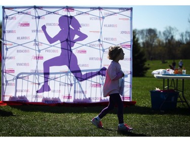Nora Wightman, 5, walks by a silhouette of a female runner during the Shoppers Drug Mart Run for Women on Sunday, May 11, 2014 near the Aviation Museum. The 5K. 10K, and 1k for children helps raise money for Women's Mental Health programs in race cities, such as Royal Ottawa.