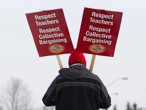 Continuing the wave of one-day walkouts, teachers of the Ottawa-Carleton District School Board carry picket signs at Roberta Bondar Public School in protest to Ontario's Bill 115, Wednesday, Dec. 12, 2012 in Ottawa. THE CANADIAN PRESS/Cole Burston