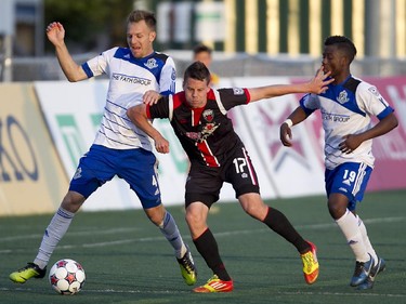 Carl Haworth (centre) battles for the ball against Edmonton FC's Neil Hlavaty (left) and Hanson Boakai (right) during the teams match-up at Keith Harris Stadium in Ottawa, May 31, 2014.
