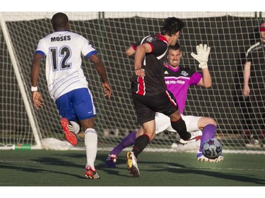 Ottawa Fury midfielder Tony Donatelli (centre) gets stopped by Edmonton FC goalkeeper Lance Parker during the teams match-up at Keith Harris Stadium in Ottawa, May 31, 2014.